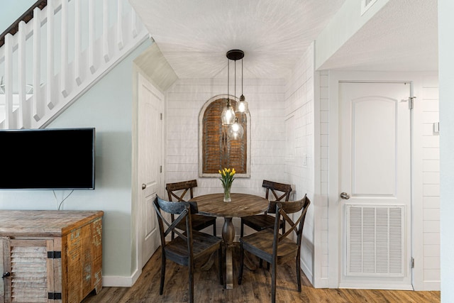 dining area with wood-type flooring and brick wall