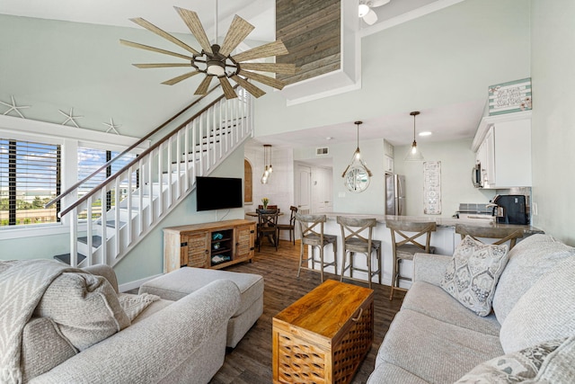 living room featuring ceiling fan, dark wood-type flooring, and a high ceiling