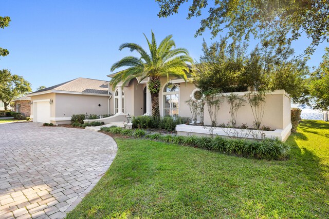 mediterranean / spanish house featuring a front yard and a garage