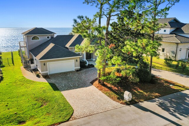 view of front of house featuring a water view, a garage, and a front lawn