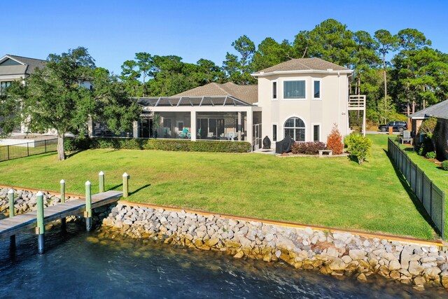 rear view of house featuring a yard, a water view, and glass enclosure