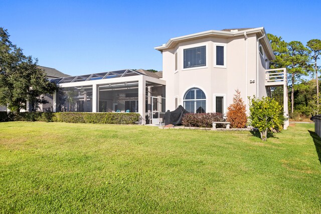 rear view of property featuring a sunroom, a lanai, and a lawn