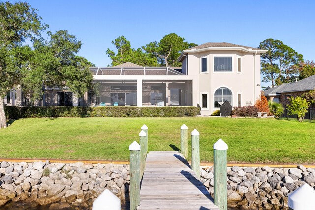 rear view of property featuring a lawn and a lanai