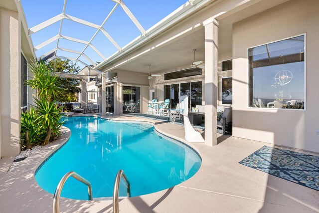 view of swimming pool with ceiling fan, a patio area, and glass enclosure