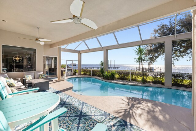 view of swimming pool featuring a lanai, a patio area, ceiling fan, and a water view