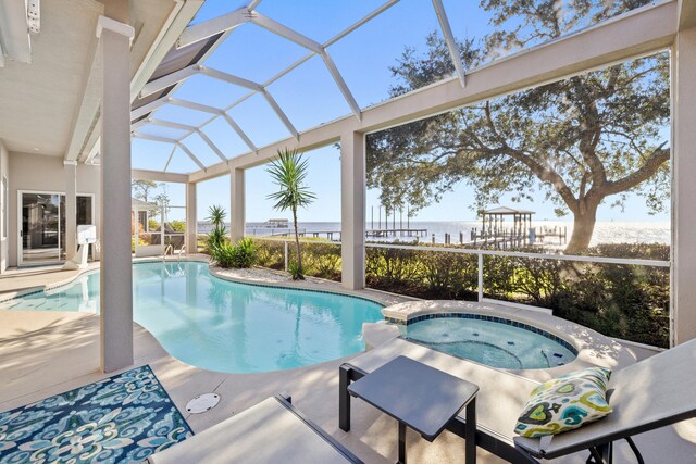 view of pool featuring glass enclosure, an in ground hot tub, a water view, and a patio