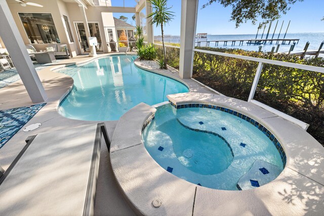 view of pool with a patio area, an in ground hot tub, a water view, and an outdoor hangout area