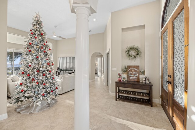 entrance foyer with ceiling fan, light tile patterned flooring, and ornate columns