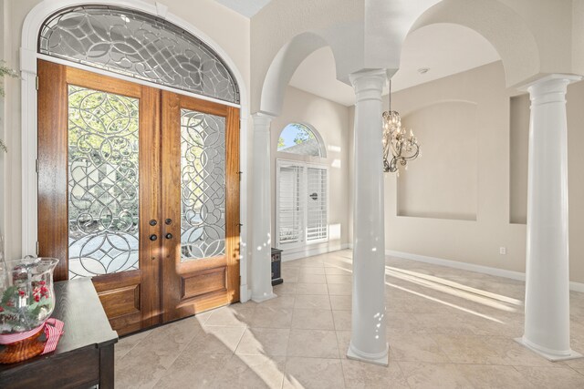 foyer entrance with an inviting chandelier, light tile patterned floors, and french doors