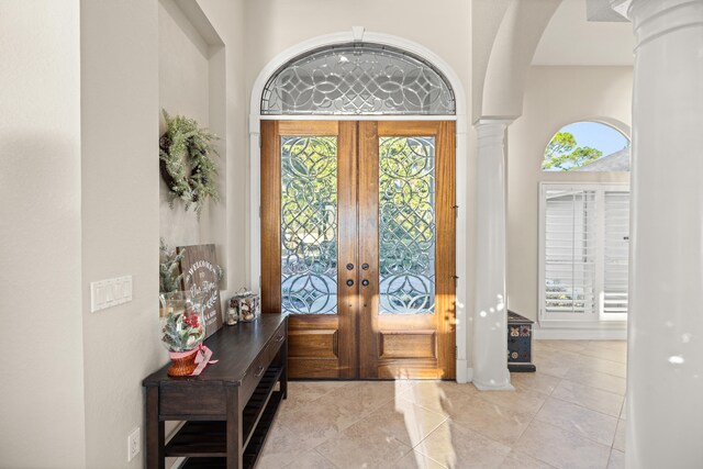 foyer entrance featuring ornate columns, a wealth of natural light, and french doors