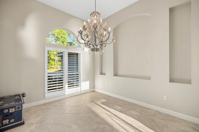 empty room featuring light tile patterned flooring and a chandelier