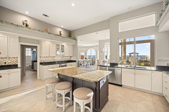 kitchen featuring sink, stainless steel dishwasher, decorative backsplash, a breakfast bar, and a kitchen island