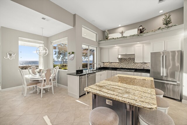 kitchen with appliances with stainless steel finishes, hanging light fixtures, a healthy amount of sunlight, and sink