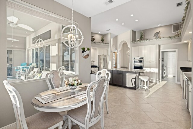 dining room with ceiling fan with notable chandelier, a healthy amount of sunlight, and light tile patterned floors