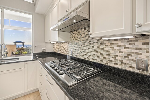 kitchen with white cabinetry, sink, tasteful backsplash, dark stone counters, and stainless steel cooktop