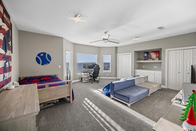 bedroom with ceiling fan, two closets, and dark colored carpet