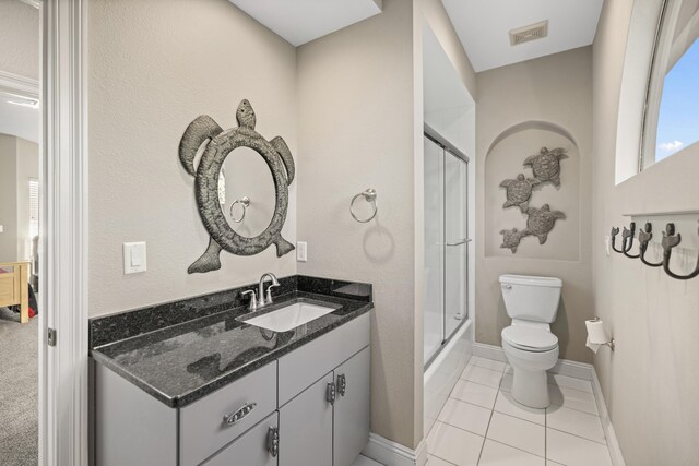 bathroom with tile patterned floors, vanity, toilet, and a shower with door