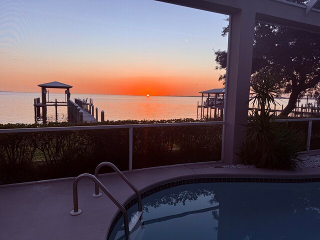 pool at dusk featuring a water view and a boat dock