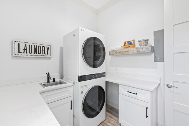 clothes washing area featuring cabinets, crown molding, sink, light hardwood / wood-style flooring, and stacked washer and clothes dryer