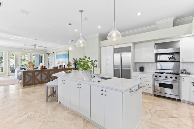 kitchen with white cabinetry, an island with sink, decorative light fixtures, and high end appliances