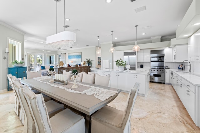 dining space with ornamental molding, sink, and french doors