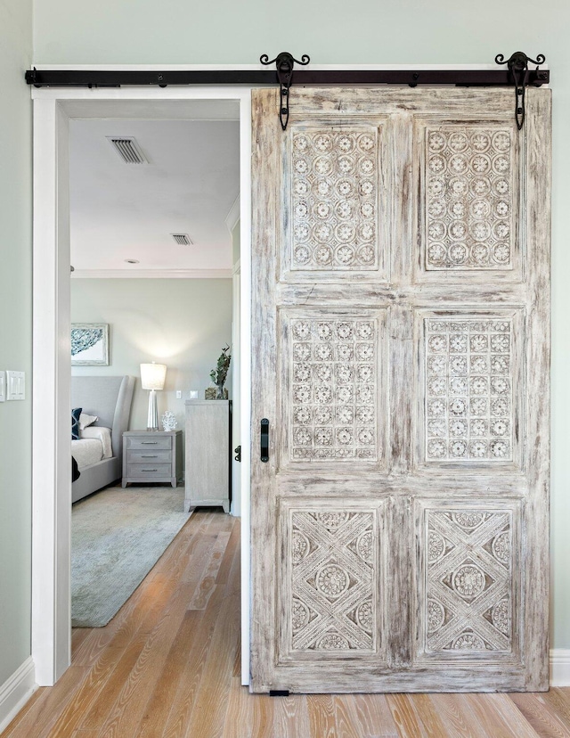 interior space featuring wood-type flooring, a barn door, and crown molding