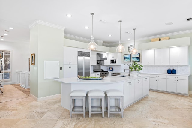 kitchen with white cabinets, built in appliances, wall chimney exhaust hood, and a large island