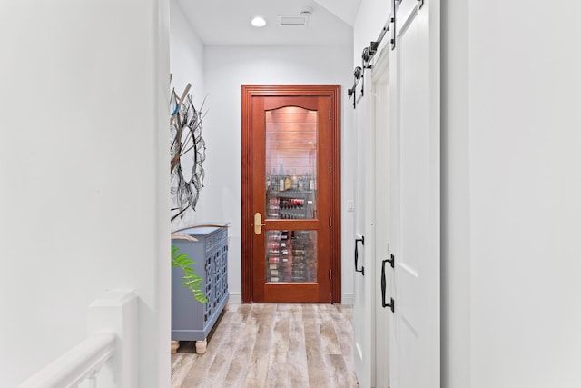 hallway featuring light wood-type flooring and a barn door