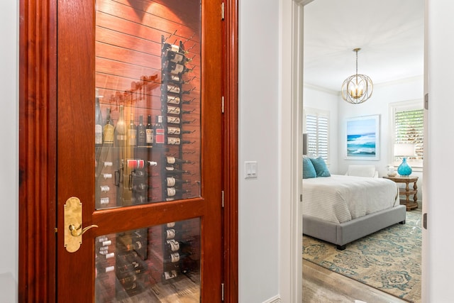 wine cellar with hardwood / wood-style floors, a notable chandelier, and ornamental molding