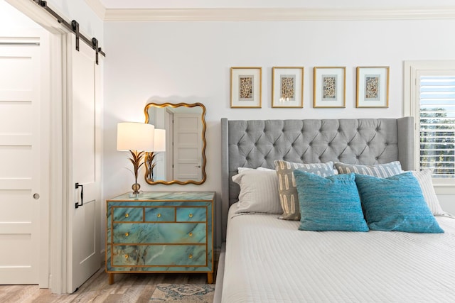 bedroom with wood-type flooring, a barn door, and ornamental molding