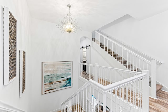 stairway featuring hardwood / wood-style floors and an inviting chandelier