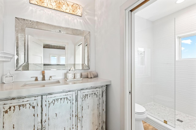 bathroom featuring vanity, toilet, and a tile shower