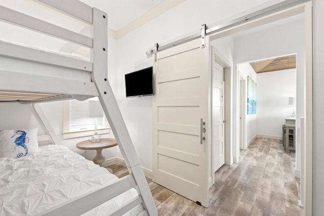 bedroom featuring a barn door and light hardwood / wood-style floors