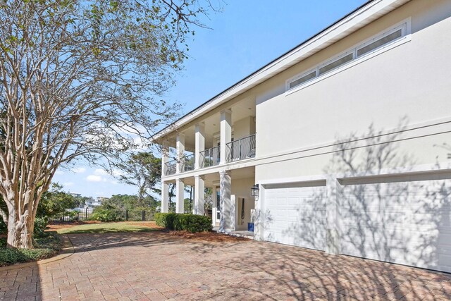 125 Emerald Rdg, Santa Rosa Beach, FL 32459 - view of property exterior featuring stucco siding, a balcony, decorative driveway, and a garage