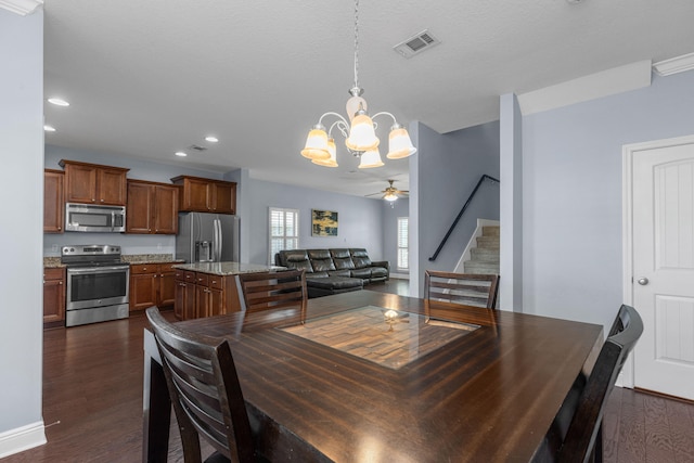 dining area with a textured ceiling, ceiling fan with notable chandelier, and dark hardwood / wood-style floors