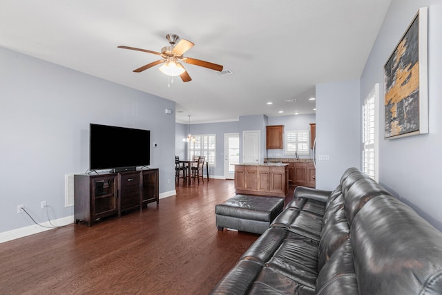 living room featuring ceiling fan with notable chandelier and dark wood-type flooring