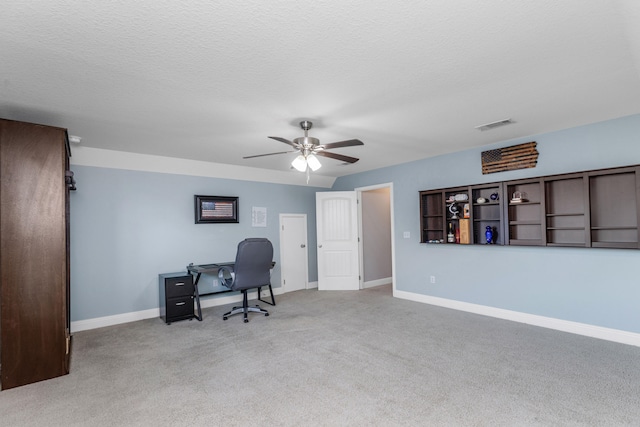 carpeted office space with ceiling fan and a textured ceiling