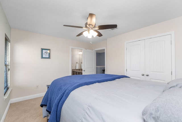 bedroom with ceiling fan, light colored carpet, connected bathroom, and a closet