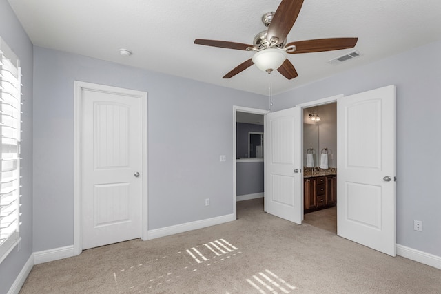 unfurnished bedroom featuring ensuite bath, ceiling fan, and light colored carpet