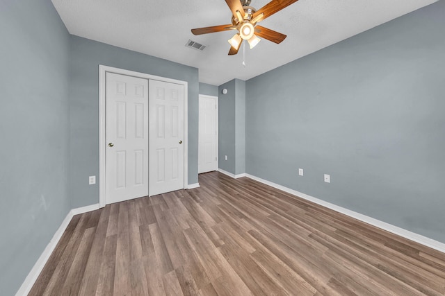 unfurnished bedroom featuring ceiling fan, a closet, hardwood / wood-style floors, and a textured ceiling