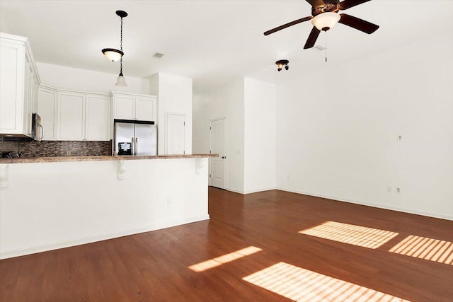 kitchen with white cabinetry, stainless steel appliances, dark wood-type flooring, and a breakfast bar area