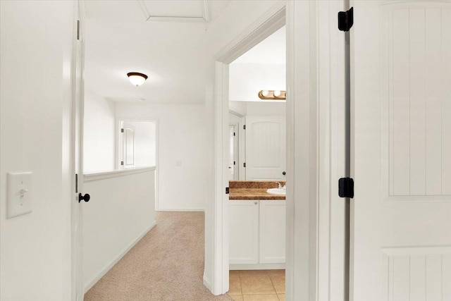 corridor featuring light colored carpet and sink