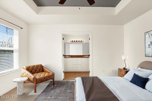 bedroom featuring ensuite bathroom, ceiling fan, and a tray ceiling