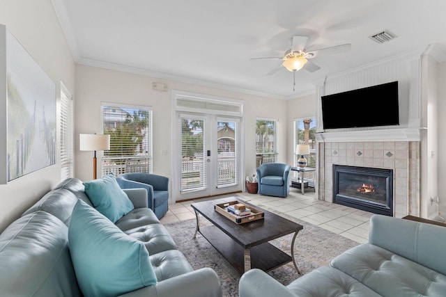 living room with ceiling fan, french doors, a fireplace, light tile patterned floors, and ornamental molding