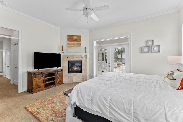 carpeted bedroom with access to exterior, ceiling fan, french doors, crown molding, and a tiled fireplace