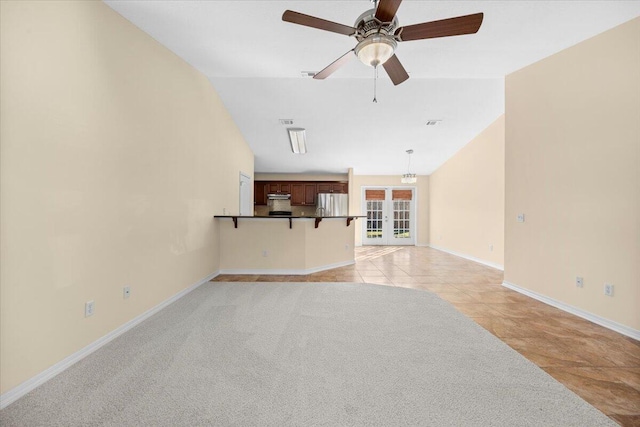 unfurnished living room featuring ceiling fan, light tile patterned floors, french doors, and vaulted ceiling