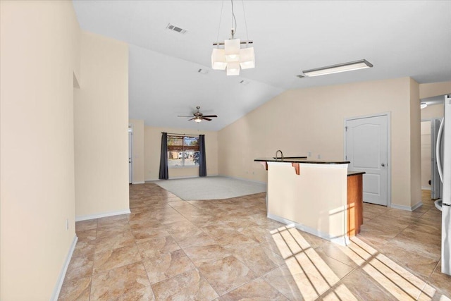 interior space featuring a breakfast bar, vaulted ceiling, ceiling fan, decorative light fixtures, and a kitchen island