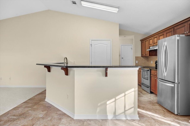 kitchen featuring stainless steel appliances, backsplash, lofted ceiling, a kitchen island with sink, and a breakfast bar