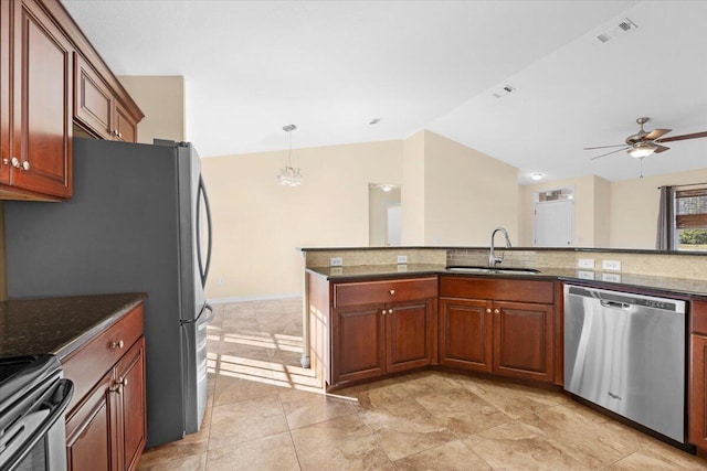 kitchen with ceiling fan with notable chandelier, sink, dark stone countertops, appliances with stainless steel finishes, and decorative light fixtures