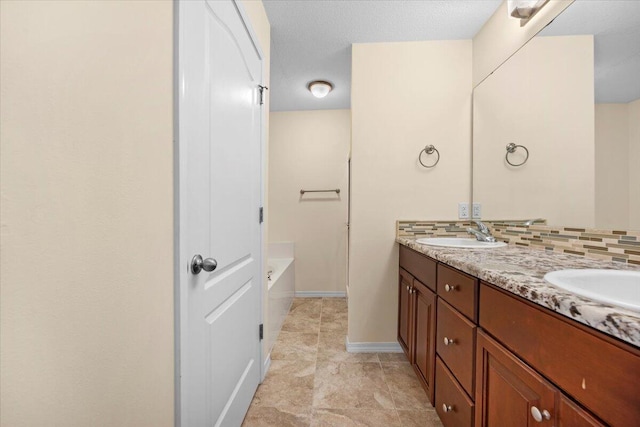 bathroom featuring vanity, decorative backsplash, and a tub